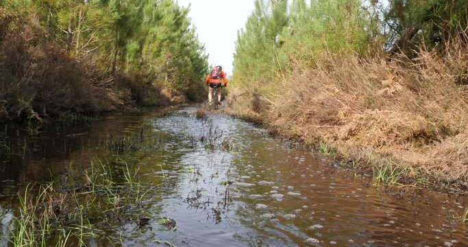 middle-aged man mountain biking in flooded paths