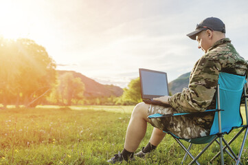 men using laptop outdoors at sunset