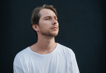Portrait of european man in white t-shirt at dark wall