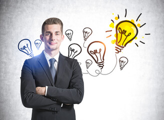 European handsome businessman with crossed arms pose looking at camera and pondering about new ideas. Concrete wall with colorful business idea lightbulb sketch. Creativity and brainstorming