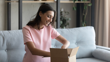 Hopeful excited young mixed race female prepare moving relocation to new house pack things to...