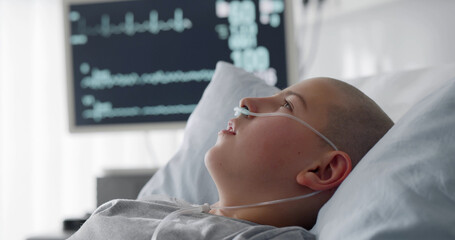 Sick child with cancer lying in hospital bed with nasal cannula