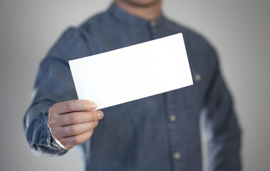 A man holds a white piece of paper. A flyer in the hands of a man. Prepared for your text. Isolated on a gray background