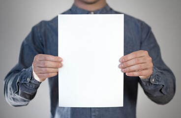 A man holds a white piece of paper. A flyer in the hands of a man. Prepared for your text. Isolated...