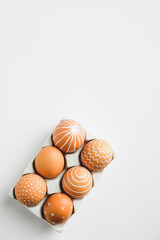 Easter eggs in holder on white background. Flat lay, top view, vertical. Happy Easter concept.