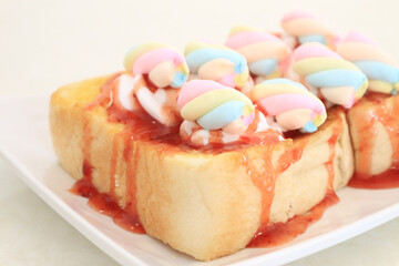 Close-up Pastel Colored Marshmallows on a slice of Bread topped with strawberry sauce.