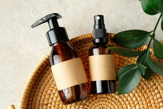 SPA natural organic cosmetics for personal hygiene. Amber glass pump and spray cosmetic bottles, green leaf in rattan container in bathroom.