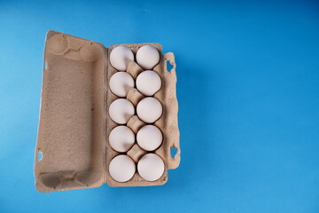 Farm raw, fresh white chicken egg in an egg box on a blue background. Eggs in carton. Eggs in the basket. Concept: a fresh egg for the morning breakfast.
