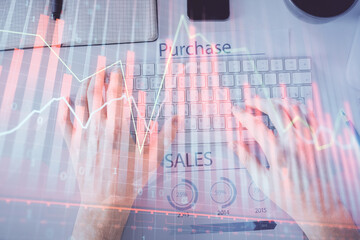 Double exposure of man's hands typing over laptop keyboard and forex chart hologram drawing. Top view. Financial markets concept.