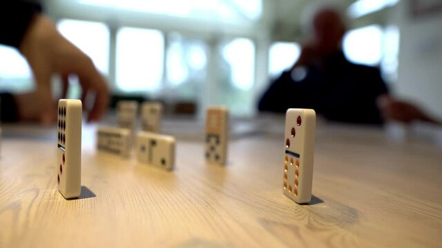 Family playing a fun game of dominoes as a group. No computers or screens. Competitive playful game of dominoes in real time with group of people