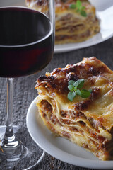 Lasagna Bolognese with a fresh Basil leaf and a glass of red wine.
