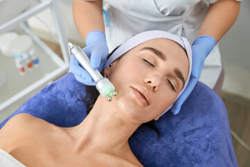 Professional cosmetologist is doing procedures for client in light cabinet