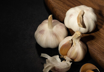 garlic heads close-up on a kitchen board and black background