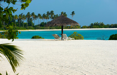 rest zone on the beach of tropical island with trees and sky