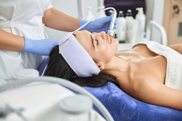 Professional cosmetologist is doing procedures for client in light cabinet
