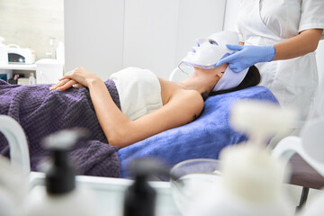 Obraz premium Professional cosmetologist is doing procedures for client in light cabinet