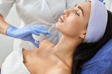 Naklejka premium Professional cosmetologist is doing procedures for client in light cabinet