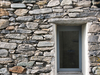 Fototapeta na wymiar Wall of a stone house with window, seen in the municipality of Centovalli in the canton of Ticino, Switzerland