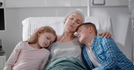 Unhappy children sitting with sick mother in hospital ward