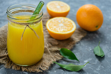 Orange juice in a jar on a gray background.
Close-up.