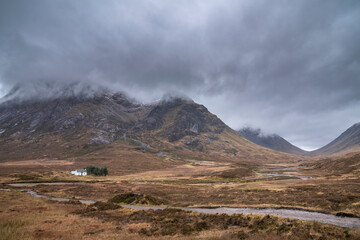 Majestic landscape image view down Glencoe Valley in Scottish Highlands with mountain ranges in dramatic Winter lighting