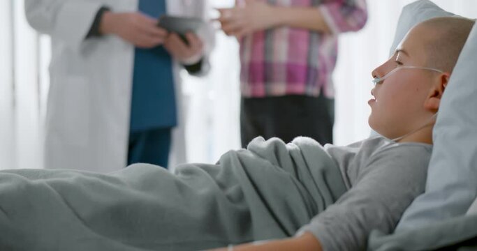 Sick Child With Cancer Lying In Hospital Bed While Mother Talking To Doctor On Background