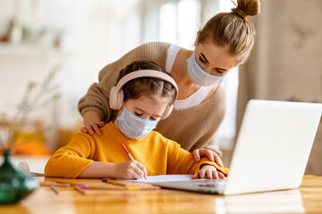 Mother and kid in protective masks with laptop doing homework together