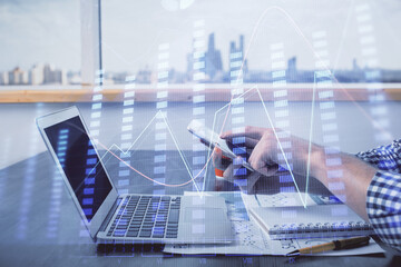 Double exposure of man's hands holding and using a digital device and forex graph drawing. Financial market concept.
