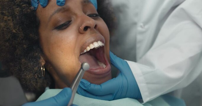Close up of dentist with assistant and scared female patient during checkup at clinic
