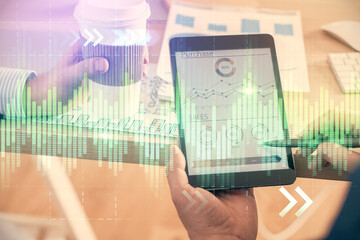 Double exposure of man's hands holding and using a phone and financial chart drawing. Market analysis concept.