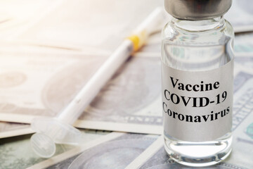 ampoule with vaccine and injectable insulin syringe on dollar bills, vaccination and treatment against covid-19, deficit, business of pharmaceutical companies, close-up, toned image