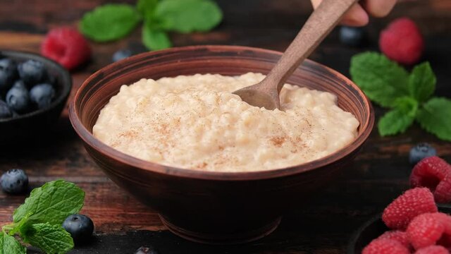 Take a bite of Rice pudding with a spoon from rustic bowl