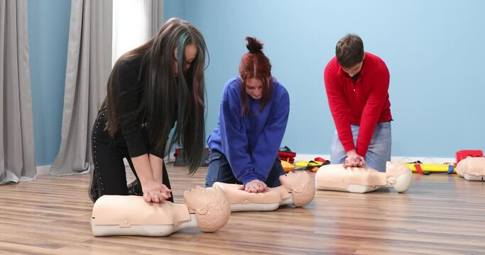 Young people try resuscitation techniques on a dummy. First aid resuscitation, CPR training, medicine, healthcare and medical concept