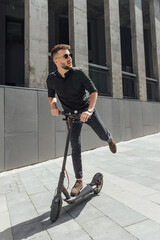 Young man riding electric scooter in urban background
