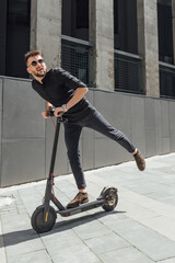 Young man riding electric scooter in urban background
