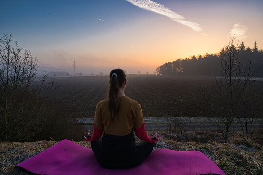 Sillouethe eine jungen Frau beim Yoga w&auml;hren eines Sonnenaufgangs