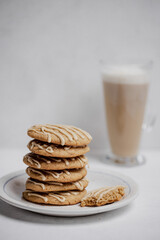 Closeup of spiced cookies with beige maple icing and latte coffee