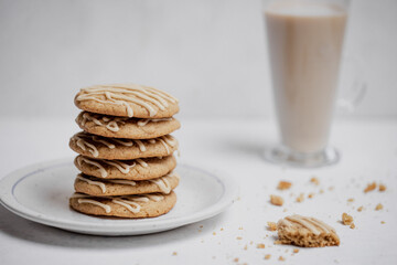 Closeup of spiced cookies with beige maple icing and latte coffee