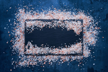 Himalayan rock salt on a slate board on dark blue background. Food background. Top view, copy space