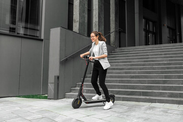 Young woman riding electric scooter in urban background