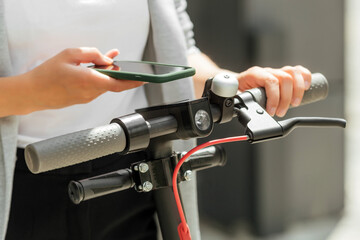 Close up image of a woman on electric scooter paying online by mobile phone