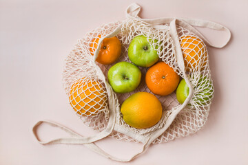 Trendy net shopping string bag with fruit on gray background. Zero waste and plastic free concept. Copy space.