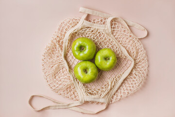 Fashionable mesh string bag with green apples on a gray background. Zero waste and plastic free concept. Copy space.