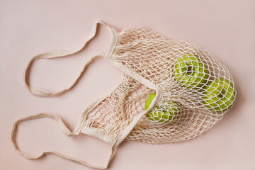 Fashionable mesh string bag with green apples on a gray background. Zero waste and plastic free concept. Copy space.