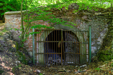 Fototapeta na wymiar Old fenced entrance to the underground with a broken lattice.