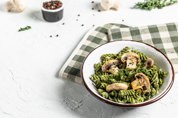 Pasta with mushrooms, spinach and green pesto. Pasta vegan bowl. banner, menu recipe place for text, top view