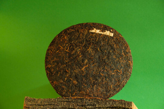 Texture Puer tea cake on tree bark. Green background. Minimalism. Copy space. Mockup.