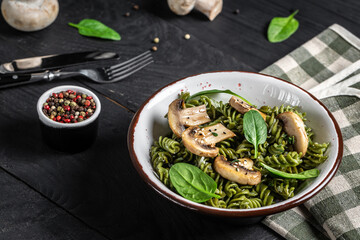 pasta penne with grilled mushrooms with spinach. Healthy vegan food. Green vegan pasta. Food recipe background. Close up