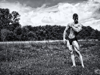 Handsome Muscular Shirtless Young Hunk Man Outdoor in Nature Standing on Grass. Showing Healthy Muscle Body While Looking away