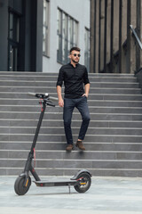 Young man going downstairs  to his electric scooter in urban background